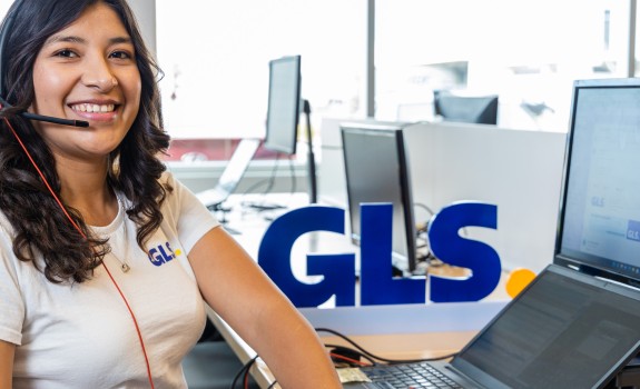 Smiling customer support agent wearing a headset at a computer.